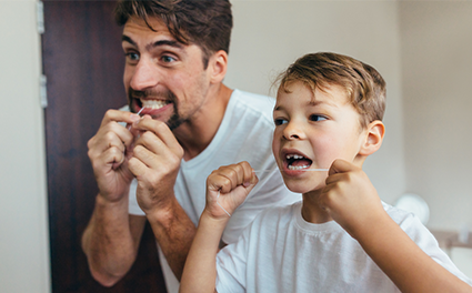 Dad and son flossing in front of mirror at home